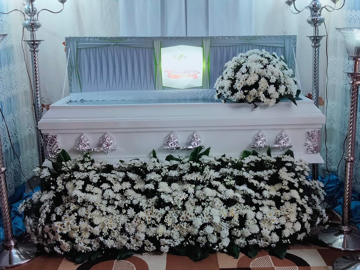 White casket with candelabras and a bed of white flowers