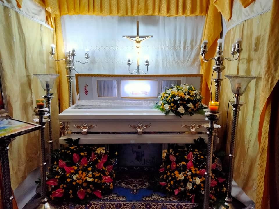 Wake prepared by Libintia Caja with gold drapes, a crucifix, candles and flowers