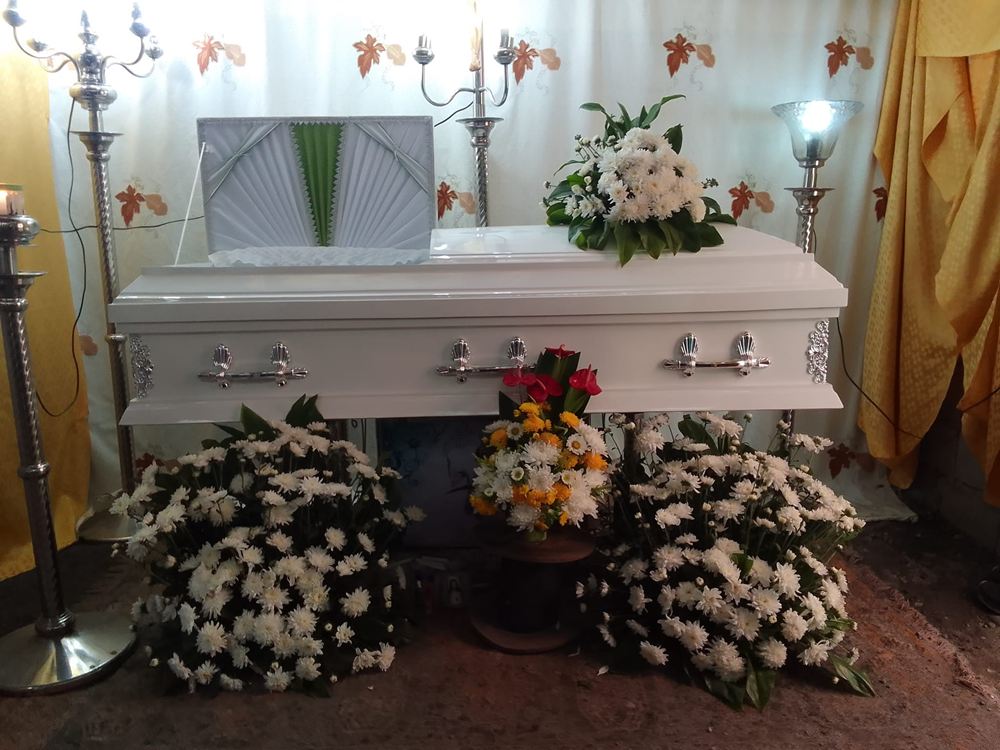 White casket with floral arrangements at a wake prepared by Libintia Caja