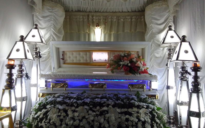 Wake setup with white drapes, lamps and a bed of white flowers