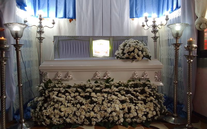 Wake setup with candelabras and white flowers in front of the casket