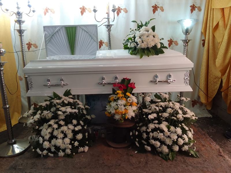 White casket with floral arrangements at a wake