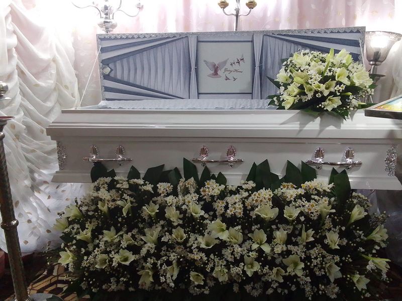 White casket with lilies and white flowers prepared for viewing