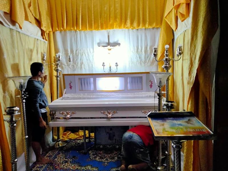 Libintia Caja staff arranging the casket and lights at a family's home